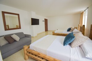 Ett hotellrum med en stor säng, en soffa, en tv och en spegel.