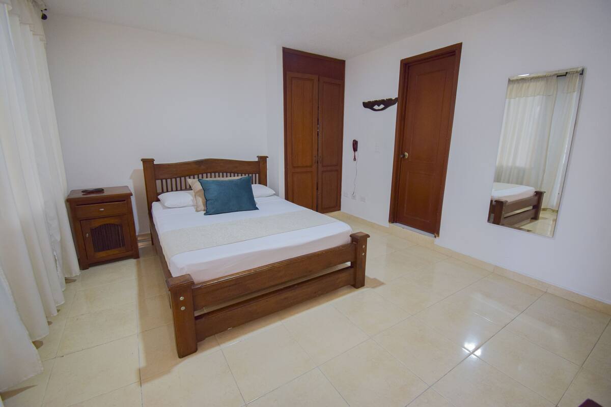 Une chambre à coucher avec un lit en bois, une table de chevet, une armoire et un miroir au mur.