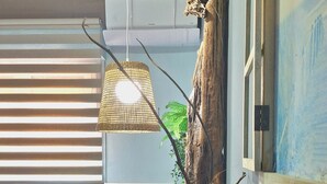 A bedroom with a bed, pillows, a hanging light, a vase, and a tree trunk. - Sunset Villa by the Sea (San Nicola l'Arena)