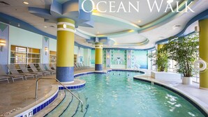 Ein Hallenbad mit einer Wassertiefe von 90 Zentimetern, umgeben von Liegestühlen und einem Wandbild mit Meereslebewesen.