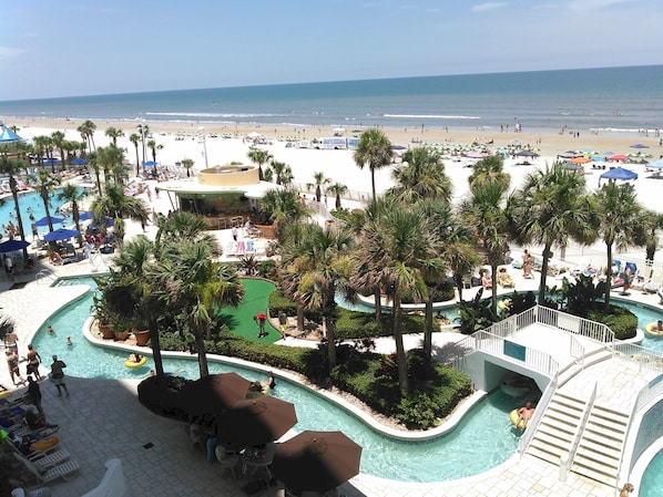 Un complexe hôtelier doté d’une piscine, de palmiers et offrant une vue sur la plage.