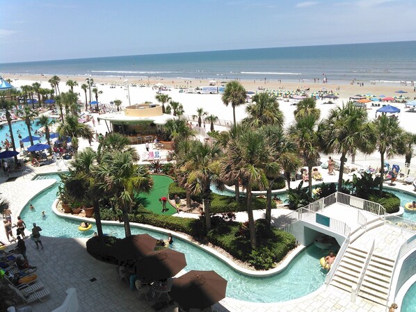 A resort with a pool area, palm trees, and a beach view.