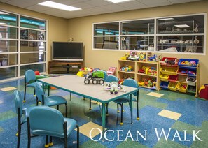 Children can play and learn in this vibrant playroom with a large table, chairs, and plenty of toys and storage.
