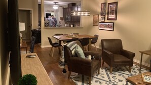 A spacious living room with a large TV, a cozy fireplace, and a dining area with a kitchen in the background.