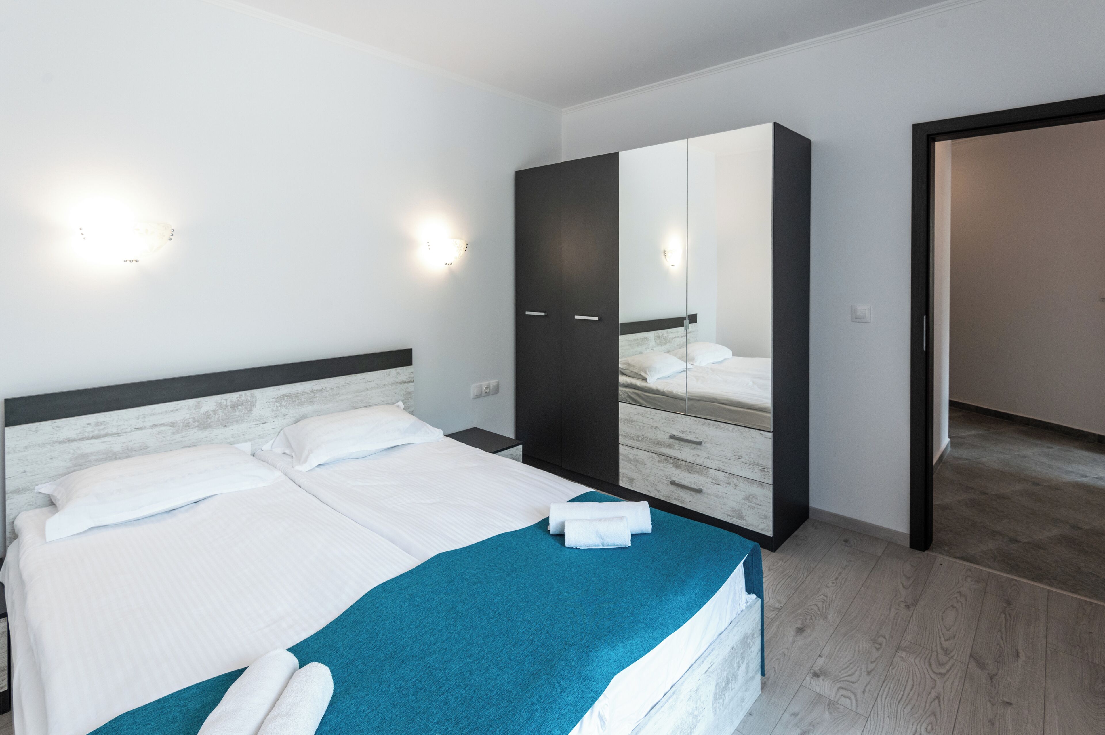 Un dormitorio con cama, armario, espejo y puerta a otra habitación.