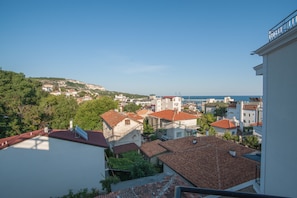 A coastal town with terracotta-roofed buildings, a clear blue sky, and a view of the sea. - Samara (Balchik)