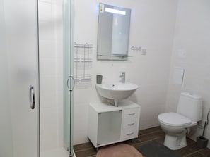 A bathroom with a glass shower enclosure, a white sink with a mirror above it, a toilet, and a cabinet with drawers. - Samara (Balchik)