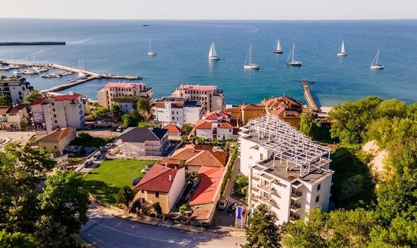 A coastal town with a marina, buildings with red roofs, and sailboats.