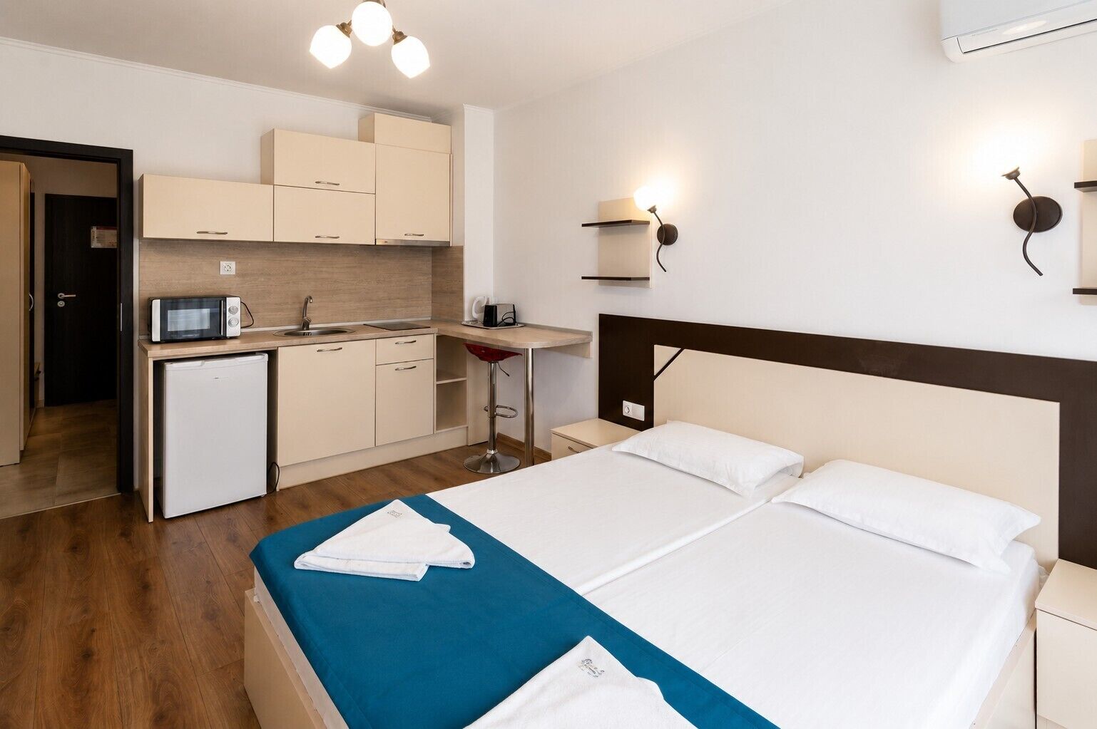 Una habitación de hotel con cama, escritorio, kitchenette y baño.