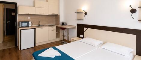 Una habitación de hotel con cama, escritorio, kitchenette y baño.