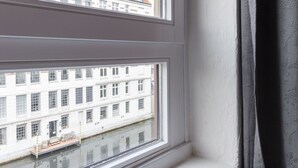 A window with a view of a building with multiple windows and a balcony. - Exclusive backyard loft, quiet, in HH-Uhlenhorst, car parkling space possible (Hamburg)