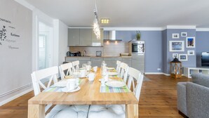 A modern kitchen with white cabinets, a wooden dining table set for six, and a chandelier. - Exclusive backyard loft, quiet, in HH-Uhlenhorst, car parkling space possible (Hamburg)