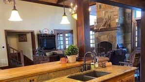 Une cuisine spacieuse dotée d’un grand îlot central, de meubles en bois et d’une cheminée en pierre.
