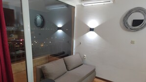 A modern living room with a sofa, a round table, and a large window overlooking a cityscape. - Villa Old Town (Ohrid)