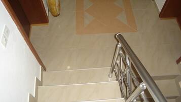 A staircase with a metal handrail, beige tiles, and a decorative tile pattern on the floor.