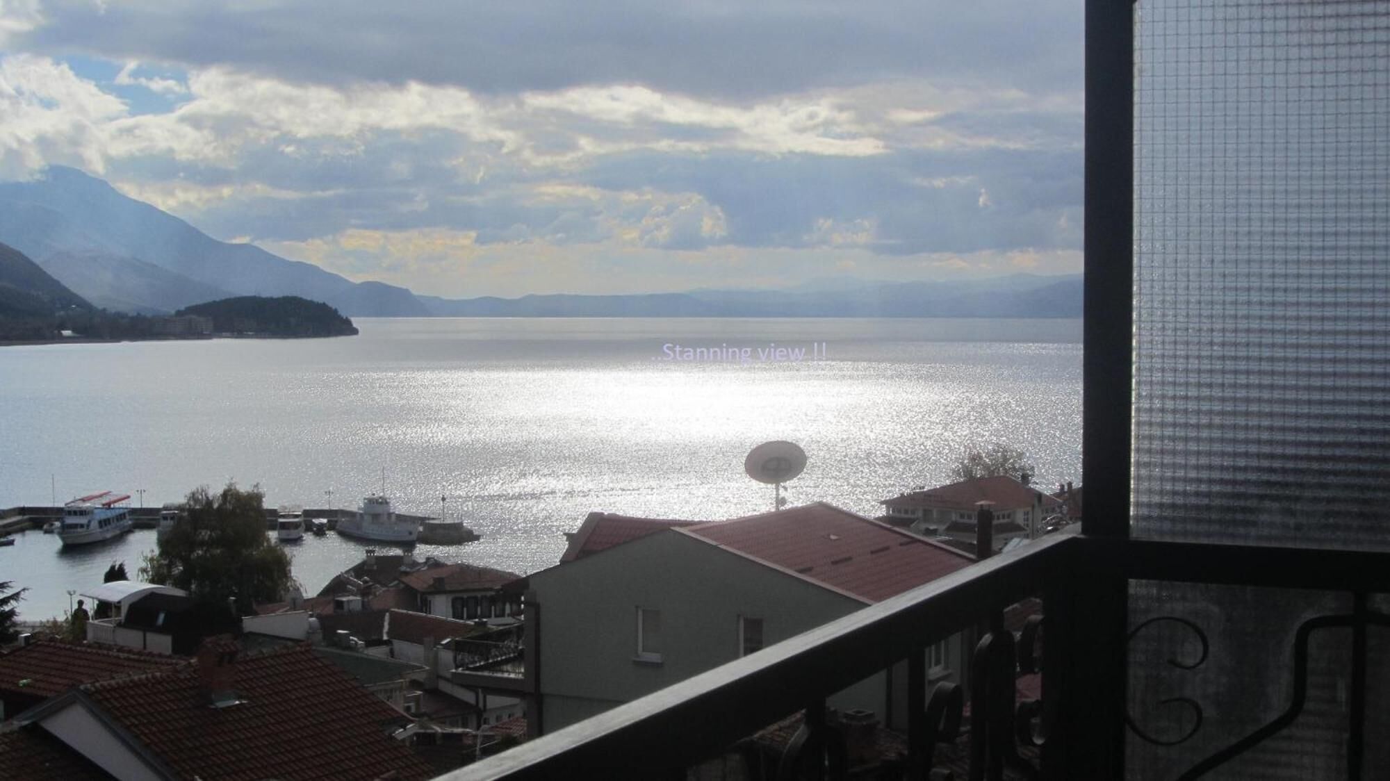 Vista di un lago con barche, una piccola isola e montagne sullo sfondo.