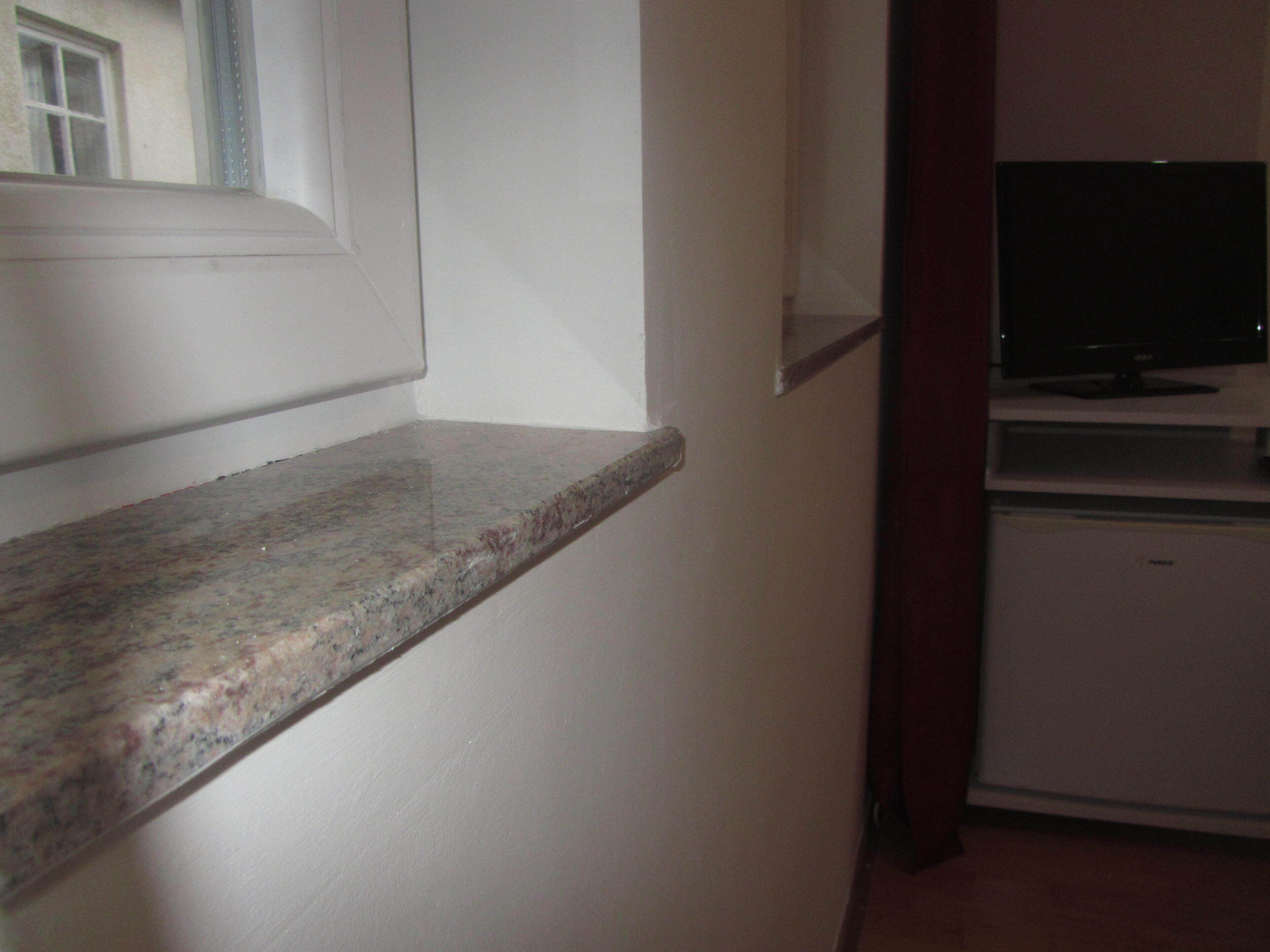 Eine Küche mit einer Granitabdeckung, einem weißen Kühlschrank und einem Fernseher auf einem Schrank.