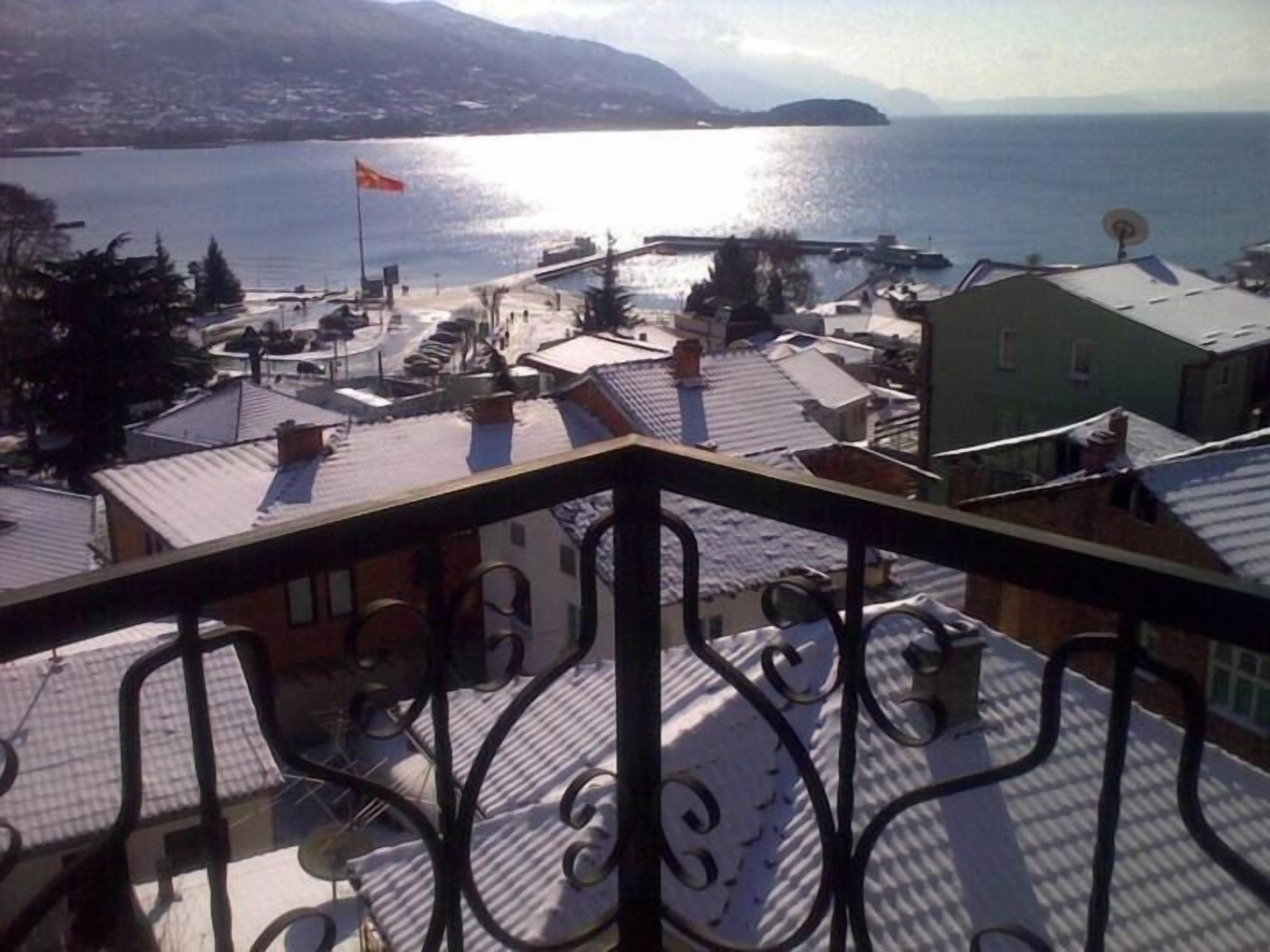 Une vue depuis un balcon donnant sur une ville côtière, avec un plan d’eau, des bâtiments et un drapeau.