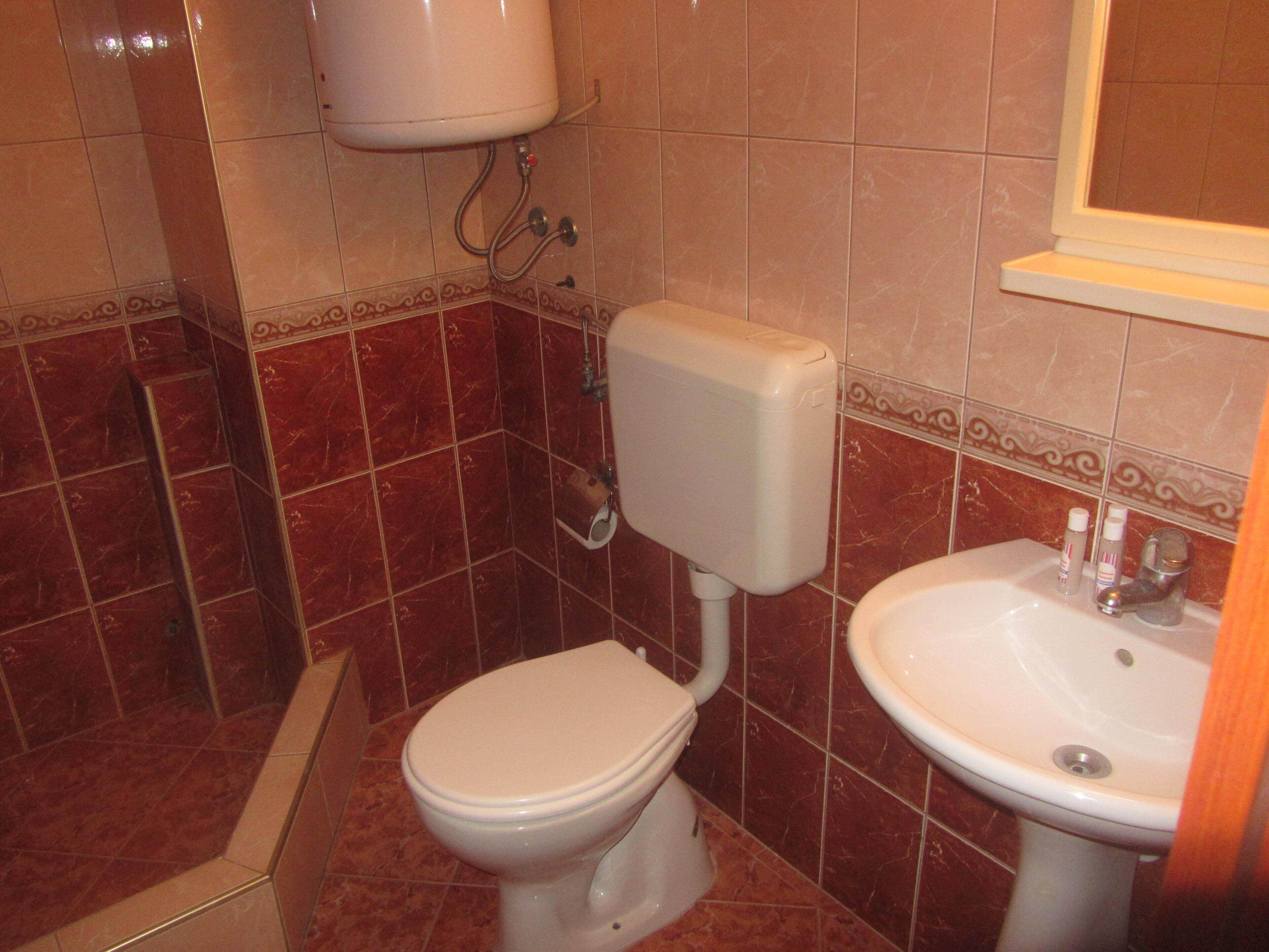 A bathroom with a toilet, sink, and a shower area.