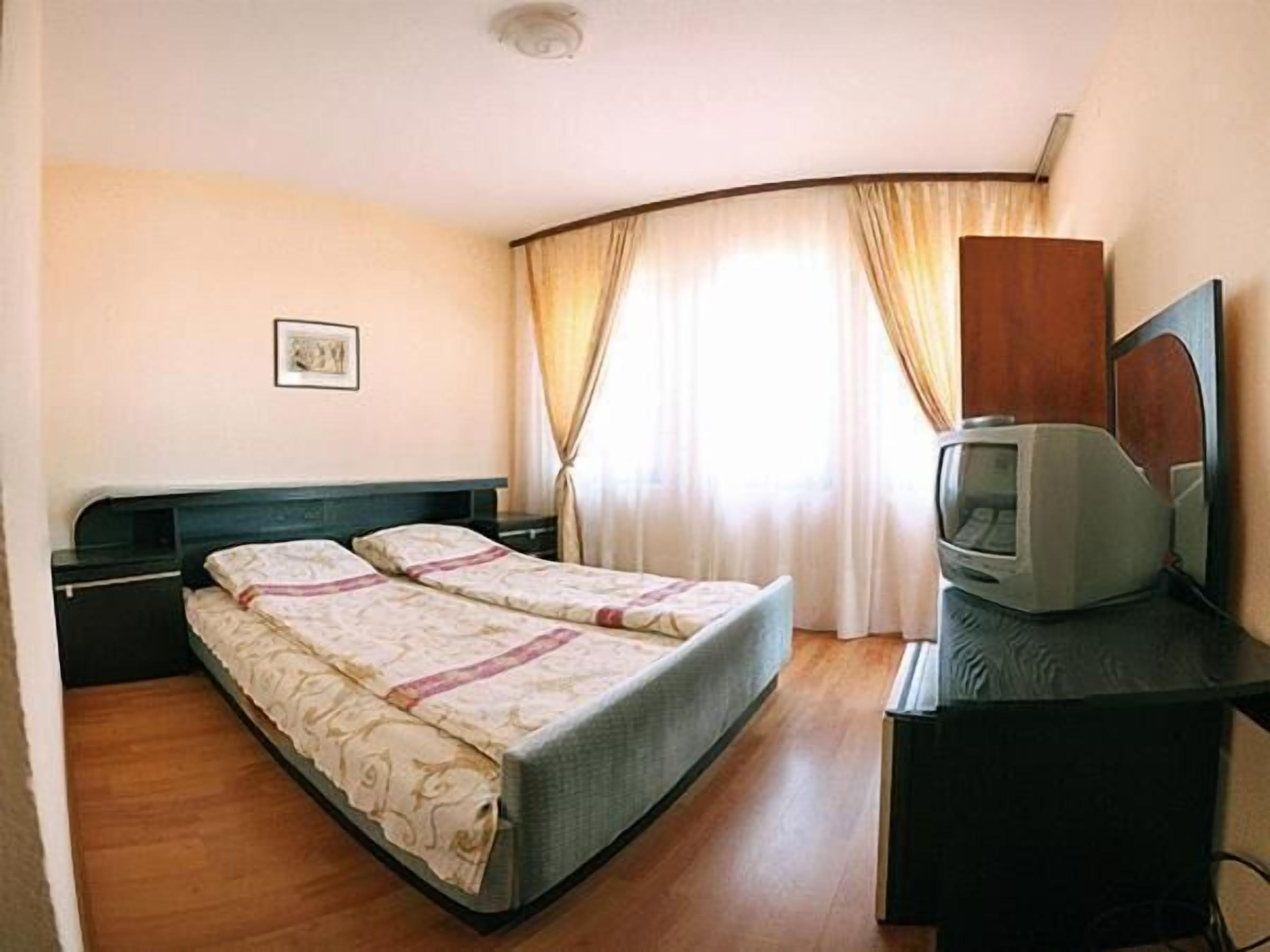 A hotel room with two beds, a television, and a desk.