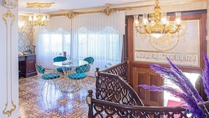 A grand room with ornate chandeliers, a round table with chairs, and a staircase with decorative railings. - Tahtakale Konağı Private & Luxury (Bursa)