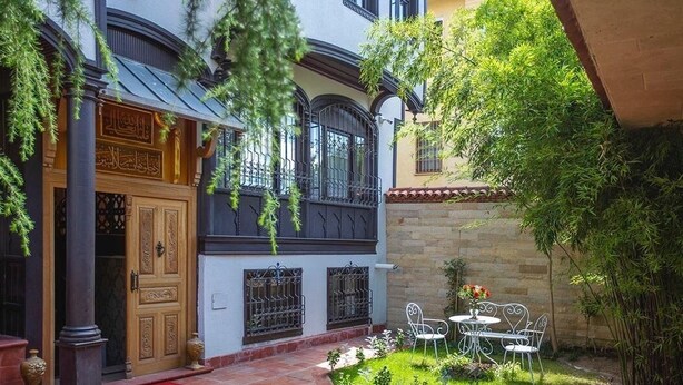A courtyard with a red carpet, white chairs, and a small garden. - Tahtakale Konağı Private & Luxury (Bursa)