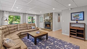 Un soggiorno moderno con un divano componibile, un camino, una televisione e una parete decorata in pietra.