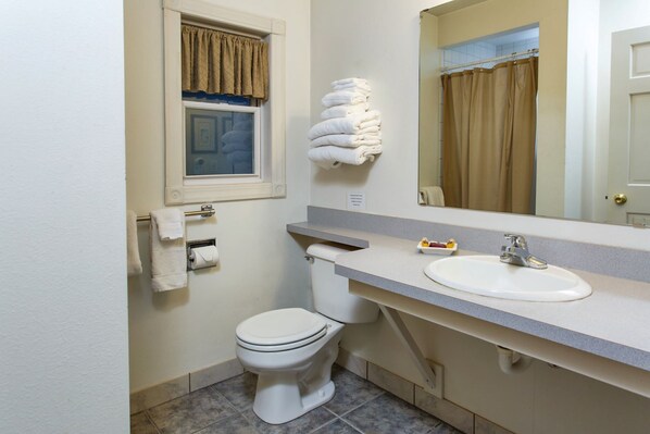 Un bagno con servizi igienici, lavandino, porta asciugamani e una finestra con tende.