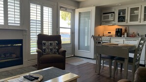 Una sala de estar con chimenea, un comedor con mesa y sillas, y una cocina con armarios y electrodomésticos.