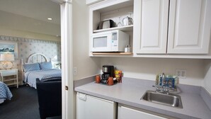 Una cocina compacta con microondas, cafetera y lavabo.