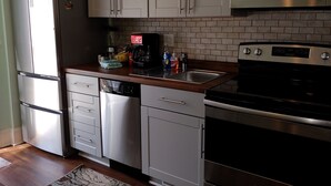A modern kitchen with stainless steel appliances, white cabinetry, and a tiled backsplash. - Beach Harbor Resort - Deluxe Apartment (Sturgeon Bay)
