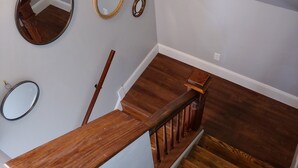 A wooden staircase with a handrail, a wooden bench, and three wall-mounted mirrors. - Beach Harbor Resort - Deluxe Apartment (Sturgeon Bay)