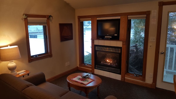 A living room with a fireplace, a sofa, a coffee table, and a television.