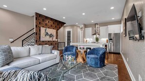 A modern living room with a white sofa, blue armchairs, and a glass coffee table.