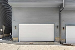 A garage with two white doors, a grey exterior wall, and a concrete driveway.