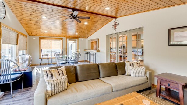 A modern living room with a wooden ceiling, a sofa, a coffee table, and a dining area with chairs and a table. - Central Scottsdale Home - Minutes to Old Town (Scottsdale)