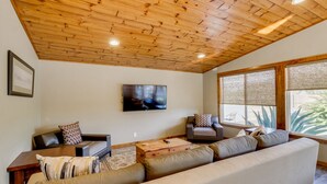 A living room with a wooden ceiling, a large TV, and a sofa. - Central Scottsdale Home - Minutes to Old Town (Scottsdale)