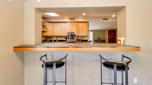A kitchen with wooden cabinets, a central island with stools, and a visible oven. - Central Scottsdale Home - Minutes to Old Town (Scottsdale)