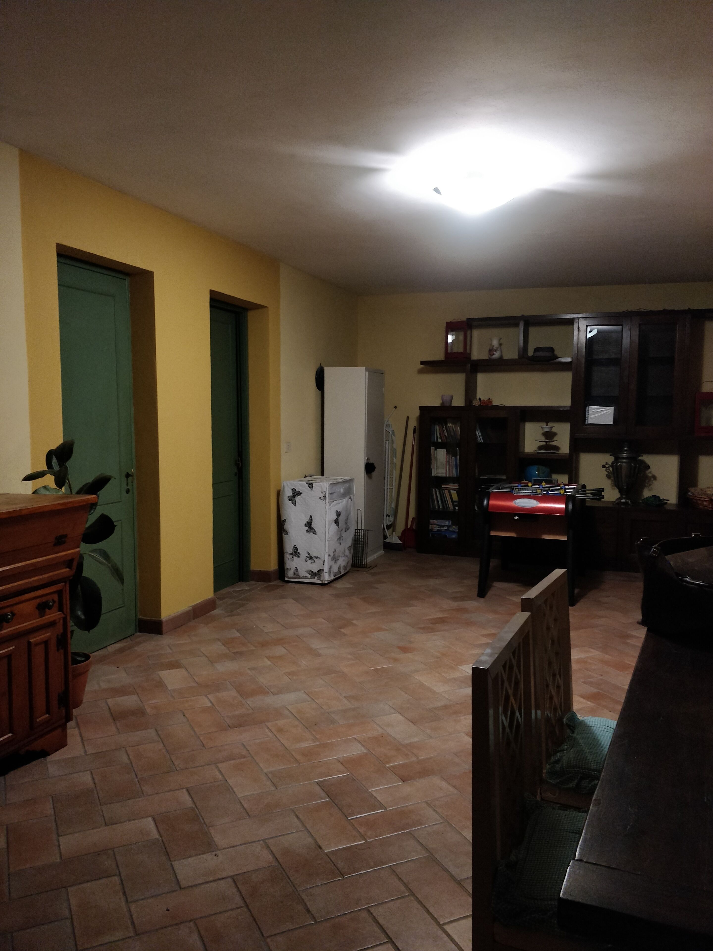 Una cocina con suelo de baldosas, un refrigerador, una mesa de comedor y un armario.