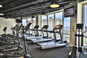 A gym with treadmills, elliptical machines, and a TV screen displaying a news channel. - ❝1522 Laketown Wharf Beach Resort with Spectacular Gulf Views❞ (Panama City Beach)
