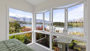 A room with large windows offering a view of a lake, mountains, and surrounding greenery. - Stay of Queenstown (Queenstown)