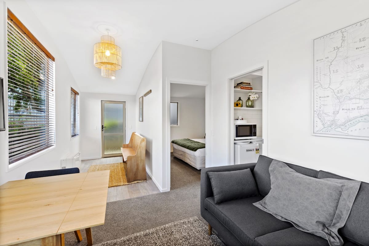 A modern living room with a grey sofa, wooden dining table, and a map on the wall.