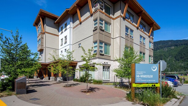 Un hotel de varios pisos con diseño moderno, que presenta una entrada destacada con un letrero que da la bienvenida a los huéspedes en Whistler.