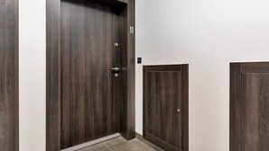 A dark wooden door with a small window, a doorbell, and a number '11' on the wall. - Modern Apartment | Balcony, Parking, Workspace (Swinoujscie)