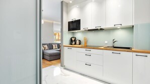 A modern kitchen with white cabinets, a microwave, a coffee maker, and a wooden countertop. - Modern Apartment | Balcony, Parking, Workspace (Swinoujscie)