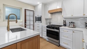 A kitchen with white cabinets, a stainless steel stove, and a wooden countertop. - Coastal Modern Beach Cottage-2 Bed/2 Bath, A/C, Vegetable Garden, Walk2Beach (Dana Point)