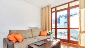 Ein modernes Wohnzimmer mit einer Couch, einem Couchtisch und Blick auf Gebäude durch große Fenster.