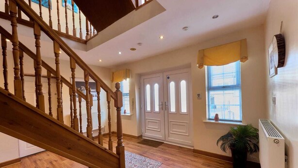 Una escalera de madera conduce a un rellano con una puerta blanca y una ventana con persianas.