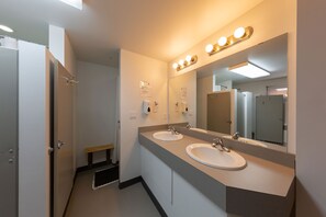 A modern bathroom with two sinks, a large mirror, and a bench.