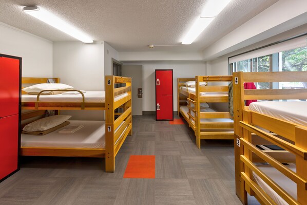 Une chambre de dortoir avec des lits superposés, une armoire rouge et une porte.